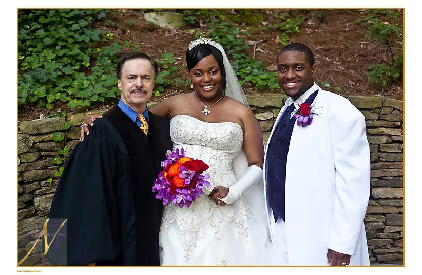 couple posing with their wedding officiant
