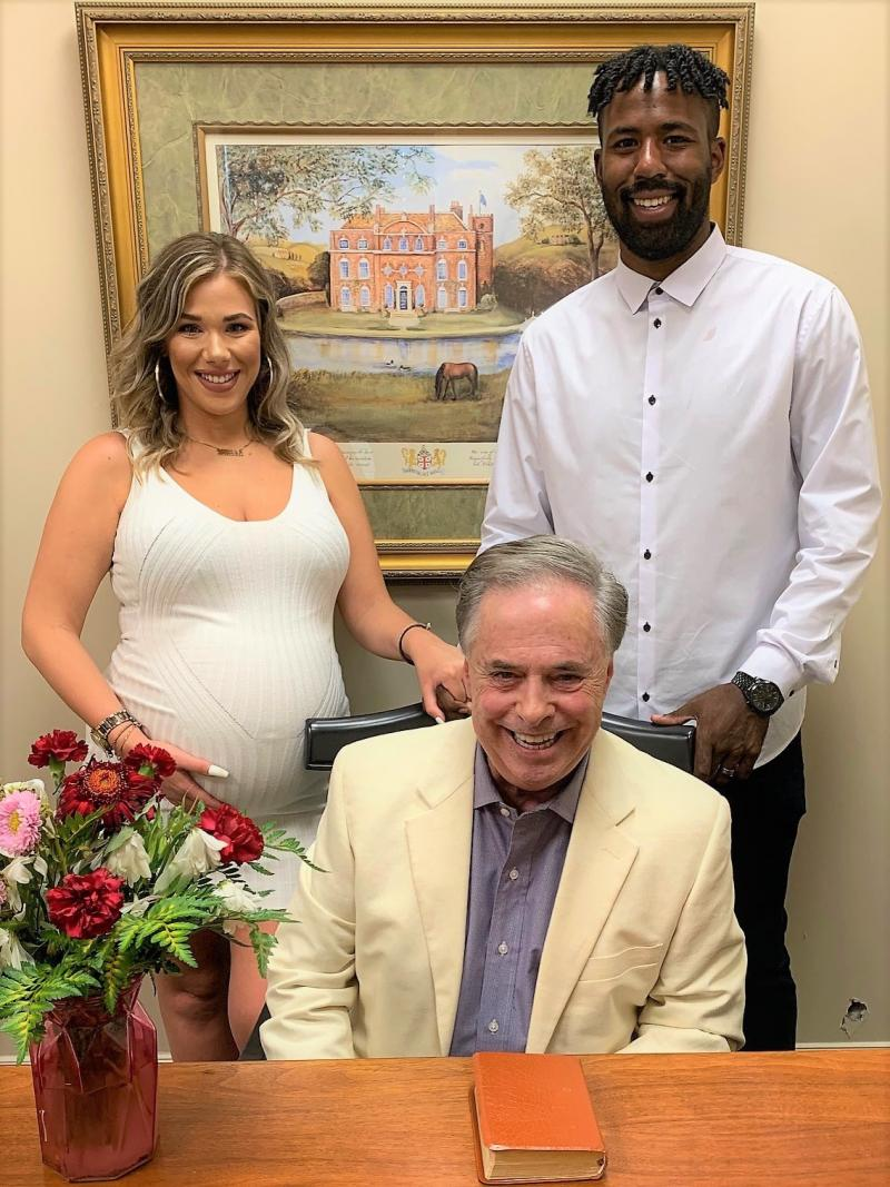 couple smiling with their wedding officiant in his office